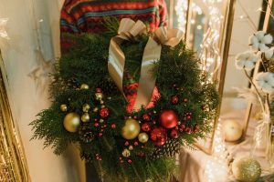 A a person wearing a sweater holding a holiday wreath