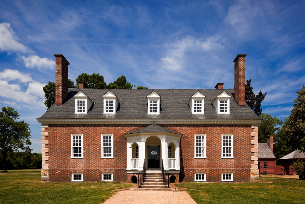 A brick house with a lot of windows and trees in the background